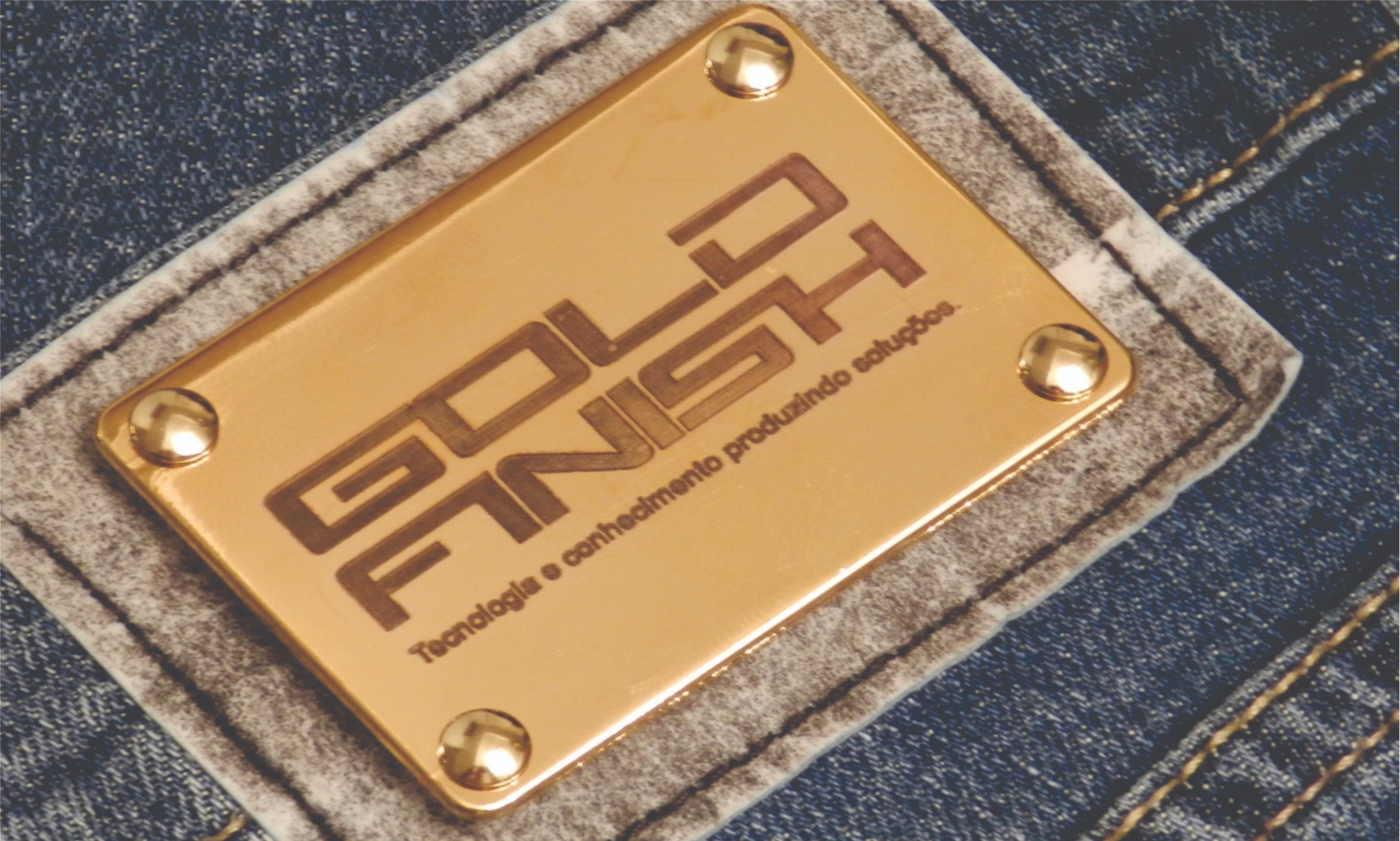 Etiqueta metálica dourada GoldFinish aplicada a tecido jeans